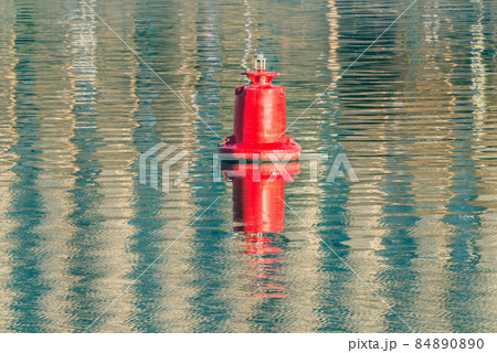 Floating red navigational buoy on water surface. 84890890