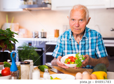 elderly man made a fresh vegetable salad at home elderly man made a fresh vegetable salad at home 84891783