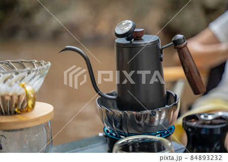 Man dripping hot coffee and camping near river at nature park. Outdoor activity and relax on holiday. 84893232