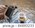Man dripping hot coffee and camping near river at nature park. Outdoor activity and relax on holiday. 84893233