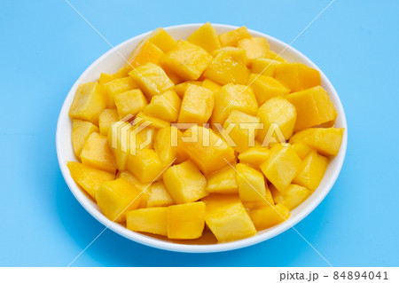 Tropical fruit, Mango cube slices in white bowl on blue background. Tropical fruit, Mango cube slices in white bowl on blue background. 84894041