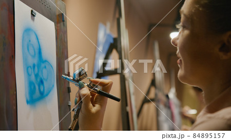 Woman artist learns to paint with airbrush with acrylic dye, paper and easel. Concept modern art, airbrushing, aerography, graffiti, aerosol spray Woman artist learns to paint with airbrush with acrylic dye, paper and easel. Concept modern art, airbrushing, aerography, graffiti, aerosol spray 84895157