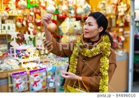 Asian female choosing decorations at Christmas fair Asian female choosing decorations at Christmas fair 84896010