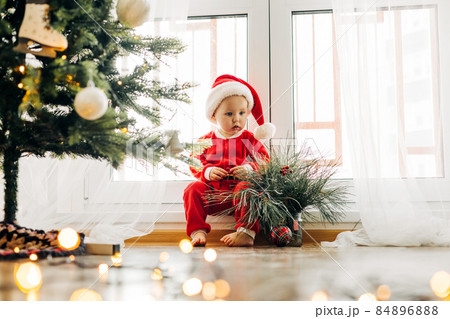 Cute baby under the tree in a New Year's costume on Christmas Eve or New Years Eve 84896888