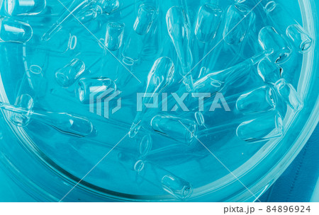 Glass medical ampoule vial for injection. Medicine is liquid sodium chloride with of aqueous solution in ampulla. Close up. Bottles ampule multicolor. 84896924