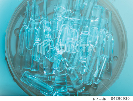 Glass medical ampoule vial for injection. Medicine is liquid sodium chloride with of aqueous solution in ampulla. Close up. Bottles ampule multicolor. Glass medical ampoule vial for injection. Medicine is liquid sodium chloride with of aqueous solution in ampulla. Close up. Bottles ampule multicolor. 84896930