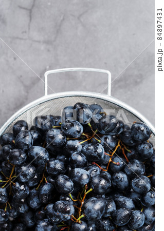 Ripe black grapes in a metal bowl on a black background. Ripe black grapes in a metal bowl on a black background. 84897431