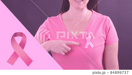 Composite image of woman showing breast cancer awareness ribbon against purple background 84899737