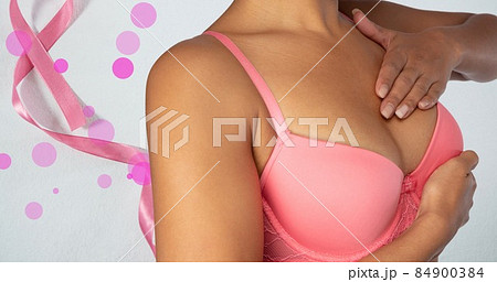 Midsection of woman in pink bra with breast cancer ribbon, copy space 84900384