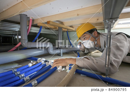 住宅の床下の水道管を点検する作業服の男性 住宅の床下の水道管を点検する作業服の男性 84900795