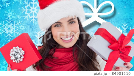 Portrait of happy young woman in santa hat with christmas presents over blue background, copy space 84901510