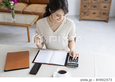 電卓を使って計算する若い女性 84902073