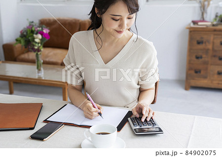 電卓を使って計算する若い女性 84902075