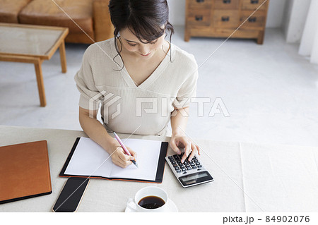 電卓を使って計算する若い女性 84902076