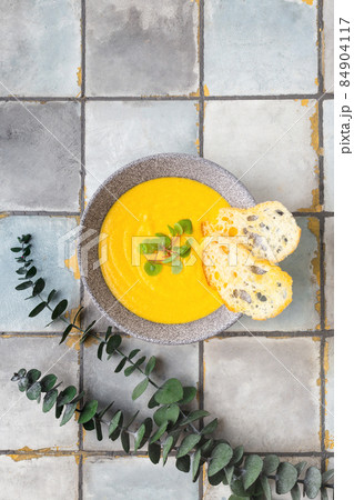 Pumpkin and carrot cream soup on white tile background with croutons. Top view. Pumpkin and carrot cream soup on white tile background with croutons. Top view. 84904117