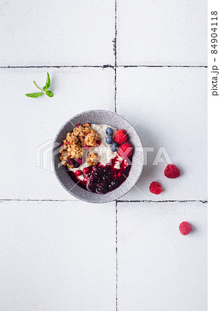 Healthy breakfast cereal porridge with berries and jam in bowl. Closeup view. 84904118