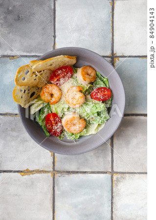 Caesar salad with shrimps and parmesan cheese on tile background 84904143