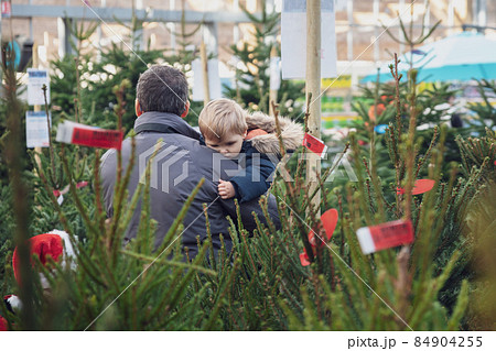 Father and kids choose a Christmas tree in a shop 84904255