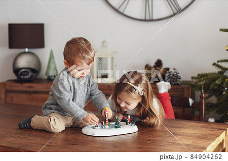 Sister and brother play with ceramic figurines for Christmas 84904262