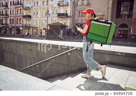 Delivery service worker carrying food order on city street Delivery service worker carrying food order on city street 84904726