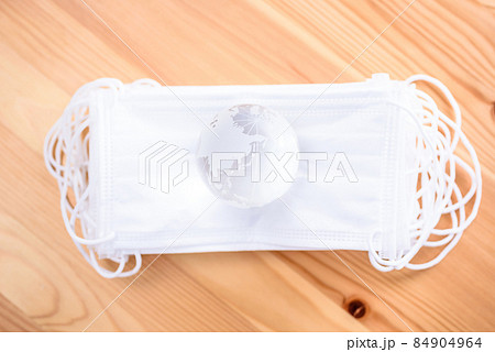 積み重ねた白いサージカルマスクの上の地球儀　新型コロナウイルス感染予防　マスクで得る安心安全 84904964