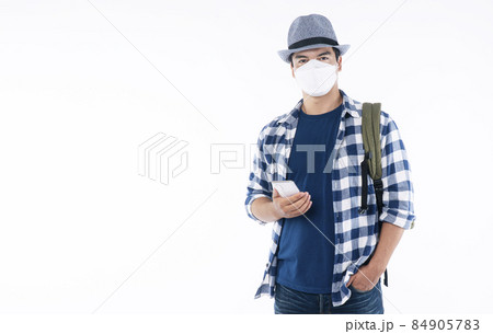 Traveler young man wear shirt, hat and face mask with backpack protect outbreak holding smartphone 84905783