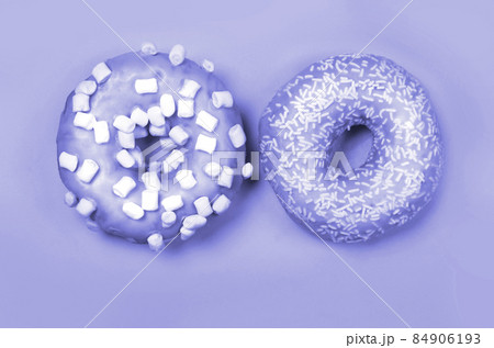 Color of year 2022. Very Peri. Violet Two donuts with icing on pastel background. Copyspace 84906193