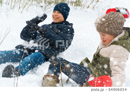 a girl and a boy are playing snowballs outside, beautiful winter weather and white snow around a girl and a boy are playing snowballs outside, beautiful winter weather and white snow around 84906854