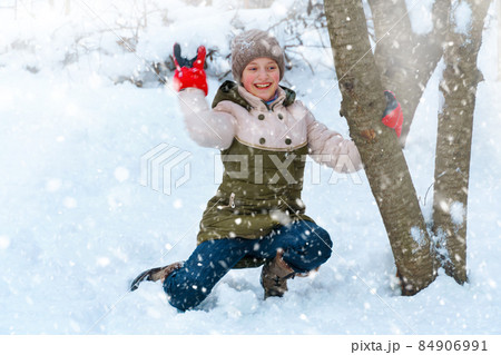 a girl plays snowballs outside, beautiful winter weather and white snow around a girl plays snowballs outside, beautiful winter weather and white snow around 84906991