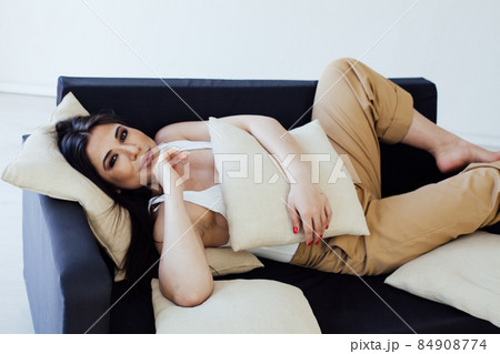 fashionable oriental brunette woman on a black sofa fashionable oriental brunette woman on a black sofa 84908774
