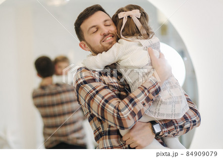 Adorable daughter with her dear father at home in gront of fit tree. Chrisrmas mood. Daughter hug father Adorable daughter with her dear father at home in gront of fit tree. Chrisrmas mood. Daughter hug father 84909079
