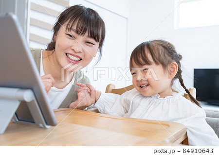 自宅のダイニングでママと一緒にタブレットを見る2歳の女の子 自宅のダイニングでママと一緒にタブレットを見る2歳の女の子 84910643