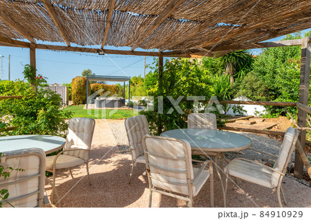Interior view of a garden gazebo in a relaxing villa hotel, lounge with table, chairs, grass and garden. Mediterranean style Interior view of a garden gazebo in a relaxing villa hotel, lounge with table, chairs, grass and garden. Mediterranean style 84910929