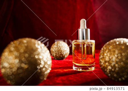 Gold christmas balls and face oil on red background Gold christmas balls and face oil on red background 84913571