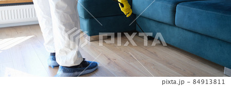Person in protective suit and gloves is treating room from painful bacteria. Disinfection of premises Person in protective suit and gloves is treating room from painful bacteria. Disinfection of premises 84913811