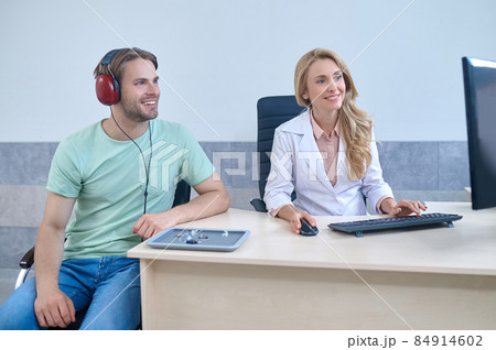 Man in headphones and woman sitting looking at computer 84914602