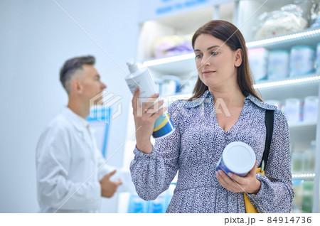 Pretty woman choosing body care products in a drugstore Pretty woman choosing body care products in a drugstore 84914736