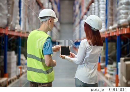 Woman showing tablet to worker with back to camera 84914834
