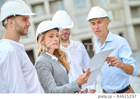 Woman with drawing listening to engineer and waiting workers Woman with drawing listening to engineer and waiting workers 84915297