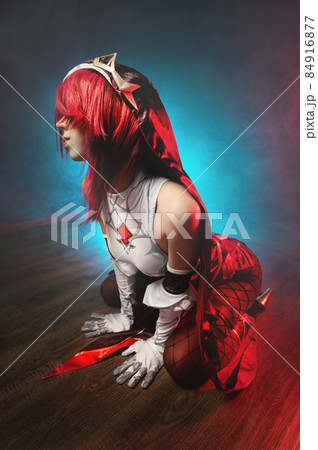 Cosplay. Studio portrait of attractive sexy young woman in anime rosary costume with red hairs and white gloves. Sexual pose on the floor in colored light Cosplay. Studio portrait of attractive sexy young woman in anime rosary costume with red hairs and white gloves. Sexual pose on the floor in colored light 84916877