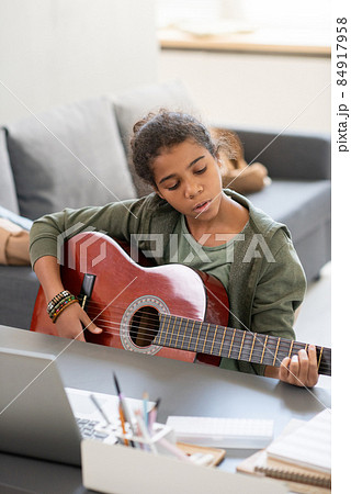 Cute preteenage girl with acoustic guitar playing at lesson Cute preteenage girl with acoustic guitar playing at lesson 84917958