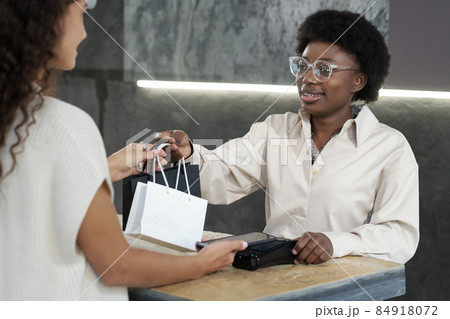 Happy young African female passing consumer paperbags with purchased goods 84918072
