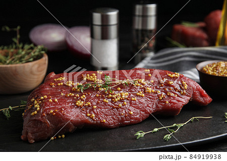 Fresh raw beef cut with thyme and mustard on table, closeup Fresh raw beef cut with thyme and mustard on table, closeup 84919938