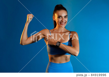 Fitness Lady Pointing Finger At Biceps Standing Over Blue Background Fitness Lady Pointing Finger At Biceps Standing Over Blue Background 84919996