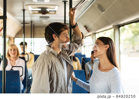 Cheerful young couple standing in bus and talking 84920250