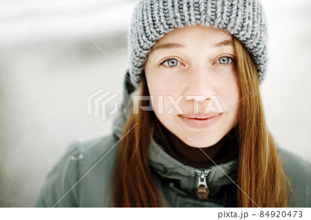 Beautiful calm smiling young woman in winter warm outfit posing outdoors in snowy park Beautiful calm smiling young woman in winter warm outfit posing outdoors in snowy park 84920473