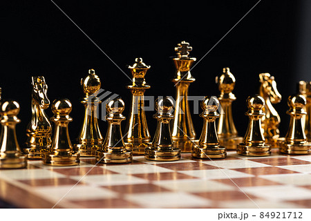 Golden chess figures standing on chessboard Golden chess figures standing on chessboard 84921712