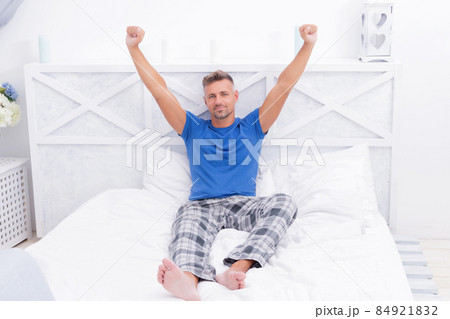 Happy man in pajamas wakeup stretching after sleep in bed, morning 84921832