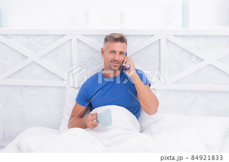 Morning call. Happy man have phone call in bed. Mobile talking. Cellular communication 84921833