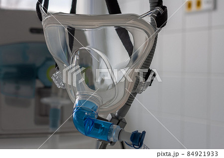 Non-invasive ventilation face mask, close up view, on background medical ventilator in ICU in hospital. 84921933